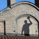 Schatten von Rauchfangkehrer am Dach mit Zylinder in der Hand